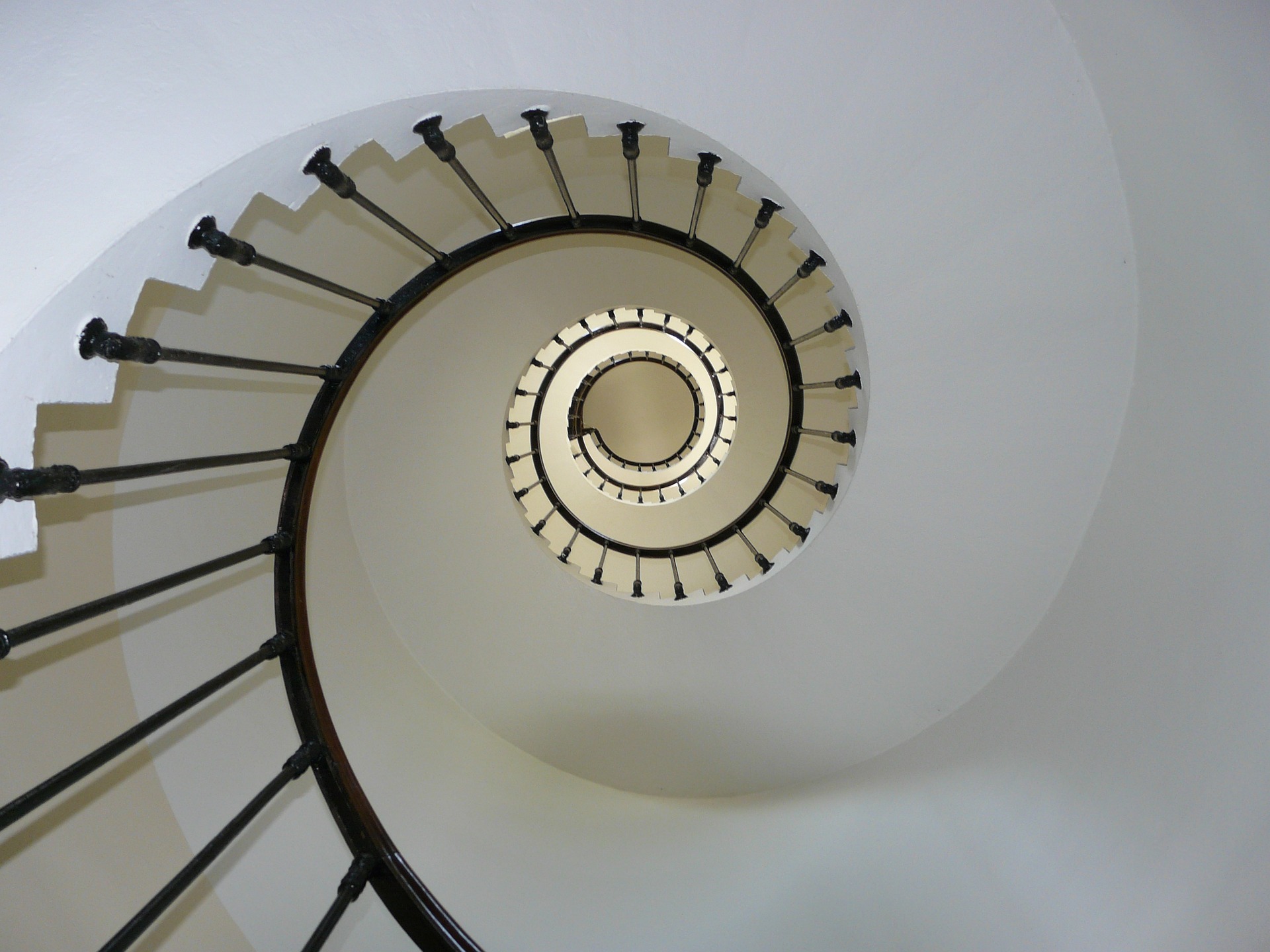 Simple black railing on spiral staircase ascending upward into the air