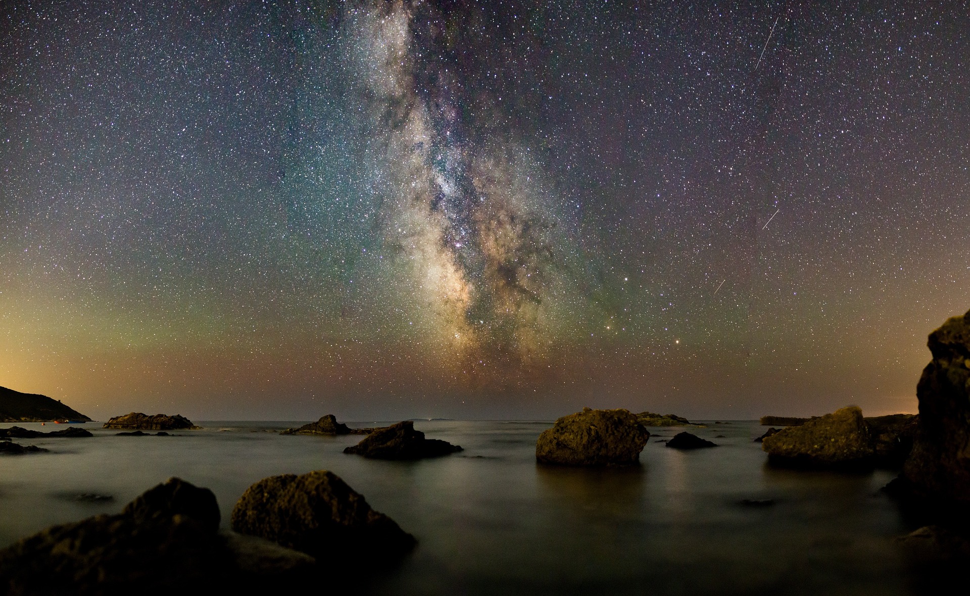 Milkyway Astrophotography over rocky boulder beach waves crashing scene