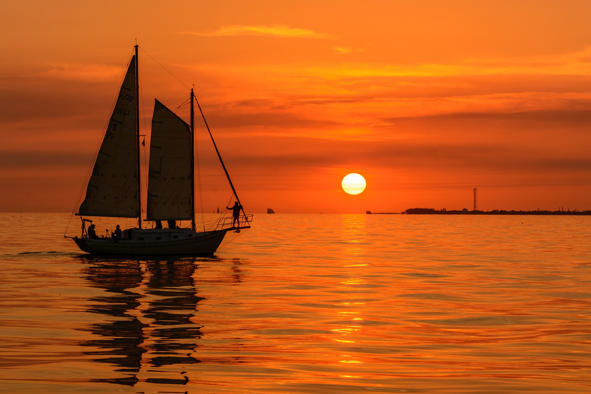 Sailboats in harbor at sunset orange sky